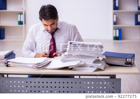 Young businessman employee unhappy with excessive work in the office Young businessman employee unhappy with excessive work in the office 92277275