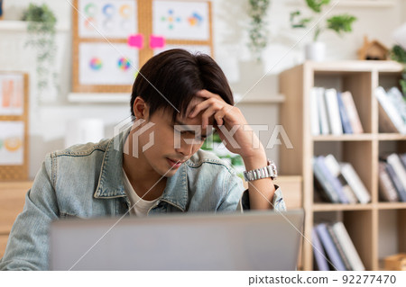 Stressed Asian man suffering from a strong migraine squeezing his head. Serious man have a headache with problem of him work. eye pain problem 92277470