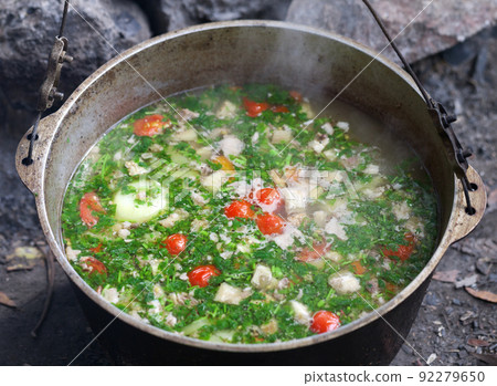 Freshly cooked hot soup in sooty cauldron at camping Freshly cooked hot soup in sooty cauldron at camping 92279650