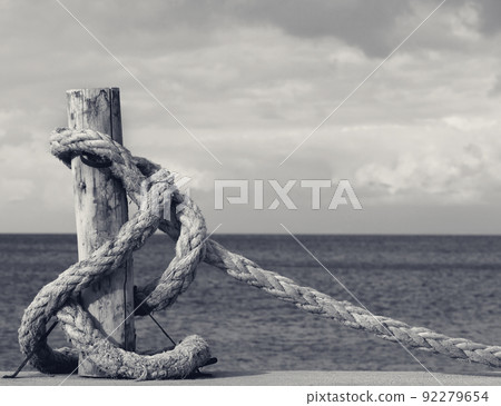 Old rope on seafront, sea and cloudy sky Old rope on seafront, sea and cloudy sky 92279654
