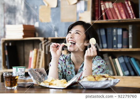 A woman eating potato chips 92279760