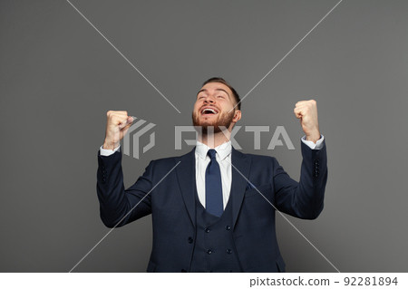 Young adult businessman having fun against grey studio wall background.  92281894