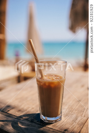 Ice coffee latte in tall glass with straw by the sea in beach bar 92281929