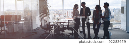 Business team standing against panoramic windows in modern office 92282659