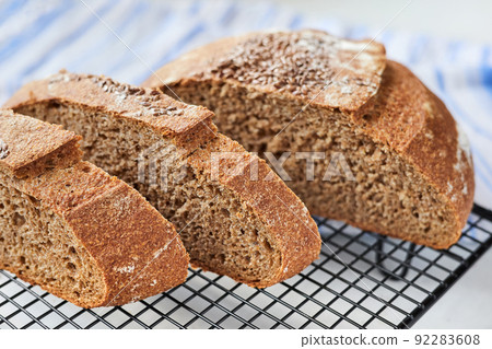 Sliced homemade round rye bread on a metal wire rack with a cloth. Close-up, selective focus 92283608