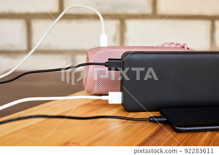 Powerbank charges smartphone and portable speaker using usb. Close-up, selective focus 92283611
