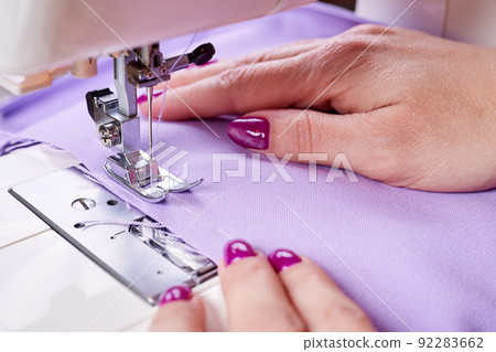 Woman sewing a dress on a sewing machine. Close-up, selective focus Woman sewing a dress on a sewing machine. Close-up, selective focus 92283662