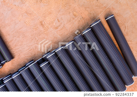 At a construction site, there are rows of PVC new black plastic pipes stacked in rows for draining systems At a construction site, there are rows of PVC new black plastic pipes stacked in rows for draining systems 92284337