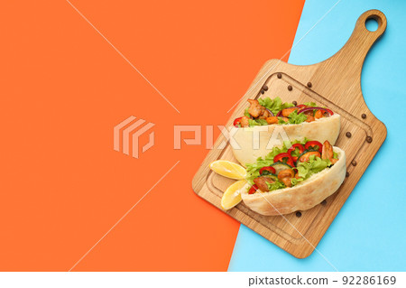 Board with pitas with chicken meat on two tone background 92286169