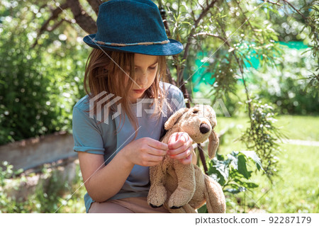 cute girl with a toy dog sitting under a tree cute girl with a toy dog sitting under a tree 92287179