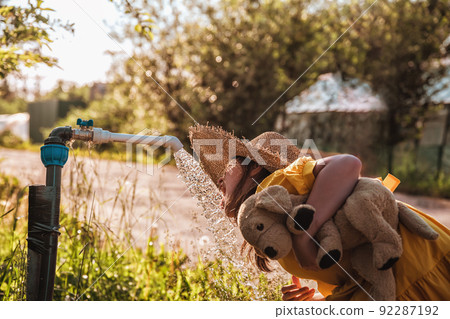 cute girl drinks water from a column outside in the summer cute girl drinks water from a column outside in the summer 92287192