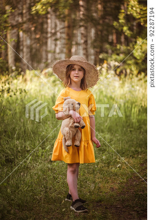 cute little girl in a yellow dress and straw hat walking through the woods cute little girl in a yellow dress and straw hat walking through the woods 92287194