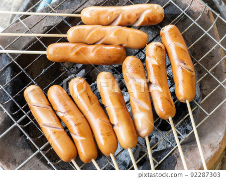The pork sausage skewers are grilled on a metal grill on the stovetop. 92287303