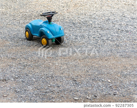 The plastic toy car with the black steering wheel on the ground. The plastic toy car with the black steering wheel on the ground. 92287305