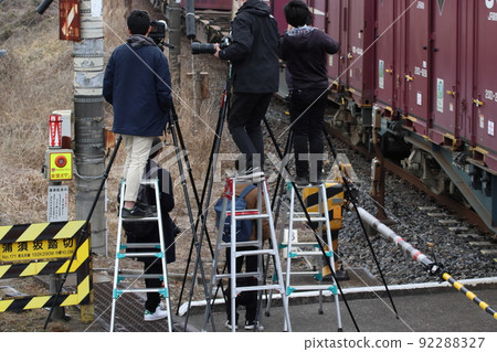 A group of photographers using stepladders on sidewalks and railroad crossings 92288327