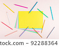 Creative pattern of multicolored pencils and papers in pastel colors on a light pink background. 92288364