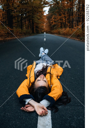 Confidence woman lying on the road with autumn tree around. New life, path choice, ambition, direction 92288762