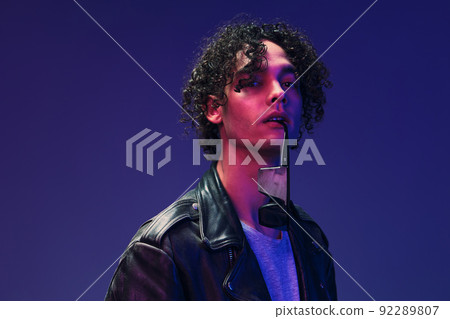 Flirted stylish curly man leather jacket eyewear looks at you posing isolated on color pink blue studio background. Cool fashion offer. Huge Seasonal Sale New Collection concept. Copy space for ad 92289807