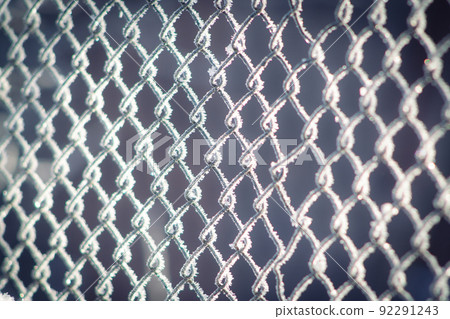 A metal wicker fence covered with ice crystals 92291243