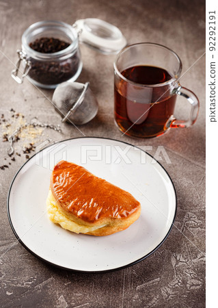 Sweet pies or buns made from yeast dough on platter and glass of tea Sweet pies or buns made from yeast dough on platter and glass of tea 92292191