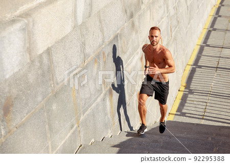 Young athlete man do morning run. Male runs up the stairs doing cardio exercises. 92295388