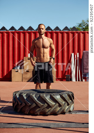 Strong man training workout lifting large tire outdoor gym. Sportive young adult caucasian guy flip big wheel on nature. Handmade equipment sport exercising helthy lifestyle concept 92295407