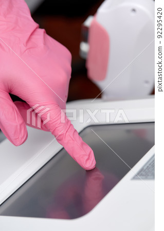 Doctor cosmetologist adjusts the device for photorejuvenation using the touchscreen Doctor cosmetologist adjusts the device for photorejuvenation using the touchscreen 92295420