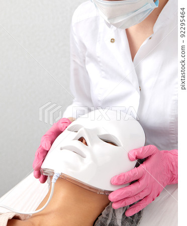 LED light anti-aging mask for facial skin care in a spa slow motion. A woman lies on a couch in a special mask. Modern technologies of beauty and health. 92295464