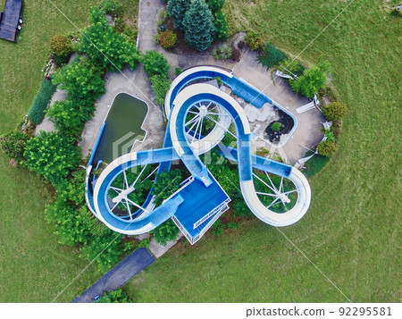 Bird's eye view of a blue water slide at an abandoned water park surrounded by grass and trees Bird's eye view of a blue water slide at an abandoned water park surrounded by grass and trees 92295581