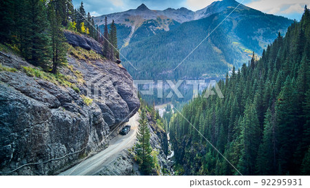 Dangerous dirt road with overhanging rocks next to cliff edge in valley of mountains Dangerous dirt road with overhanging rocks next to cliff edge in valley of mountains 92295931