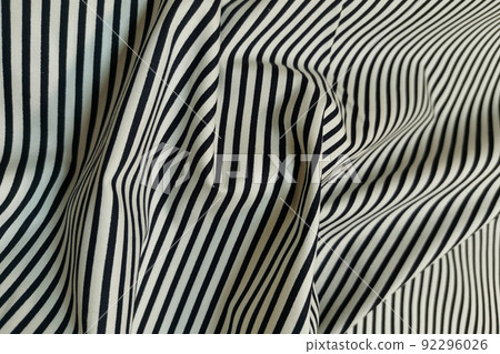 White fabric with black stripes. Crumpled or wavy fabric texture background. Abstract linen cloth soft waves. Natural yarn. Smooth elegant luxury cloth texture. Concept for banner or advertisement. White fabric with black stripes. Crumpled or wavy fabric texture background. Abstract linen cloth soft waves. Natural yarn. Smooth elegant luxury cloth texture. Concept for banner or advertisement. 92296026