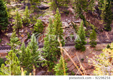 Train track through rocky mountain slop with scattered pine trees 92296258