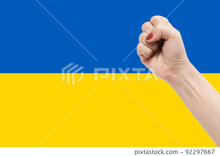 Woman hands with fist gesture on Ukraine flag color background 92297667