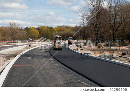 Asphalt rollers paving new asphalt driving in line one near another. New road construction. Selective focus. 92299206