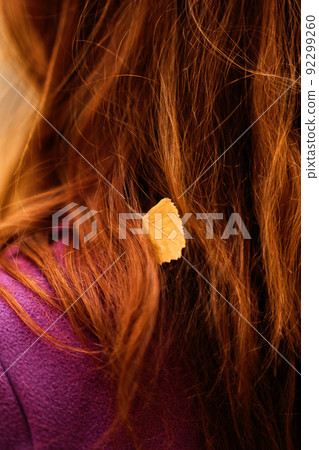 Autumn portrait of candid beautiful red-haired girl with fall leaves in hair. 92299260