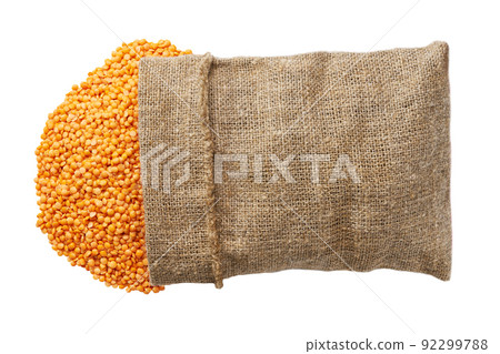 Organic red lentils in sack isolated on white background flat lay. Grains are scattered out of bag top view. 92299788
