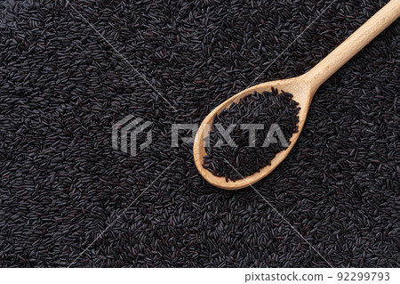 wooden spoon with black rice on a thai black rice background close-up top view. 92299793