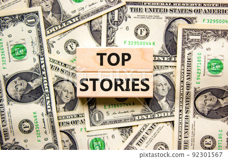 Top stories symbol. Concept words Top stories on wooden blocks on a beautiful background from dollar bills. Business story and top stories concept, copy space. Top stories symbol. Concept words Top stories on wooden blocks on a beautiful background from dollar bills. Business story and top stories concept, copy space. 92301567