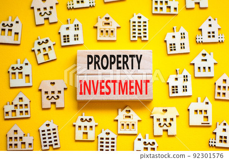 Property investment symbol. Concept words Property investment on wooden blocks on a beautiful yellow table yellow background. Wooden house model. Business Property investment concept. Copy space. 92301576