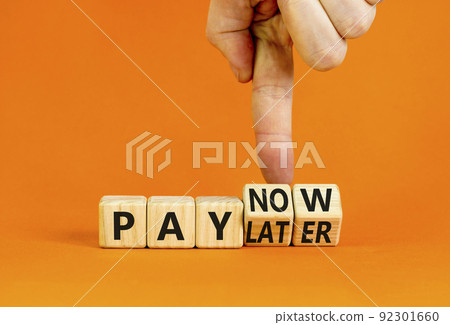 Pay later or now symbol. Businessman turns wooden cubes and changes concept words Pay later to Pay now. Beautiful orange table orange background. Business pay later or now concept. Copy space. 92301660