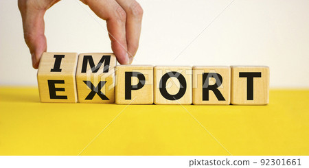 Import or export symbol. Hand is turning a cube and changes the word 'import' to 'export'. Beautiful yellow table, white background. Business and import or export concept, copy space. Import or export symbol. Hand is turning a cube and changes the word 'import' to 'export'. Beautiful yellow table, white background. Business and import or export concept, copy space. 92301661