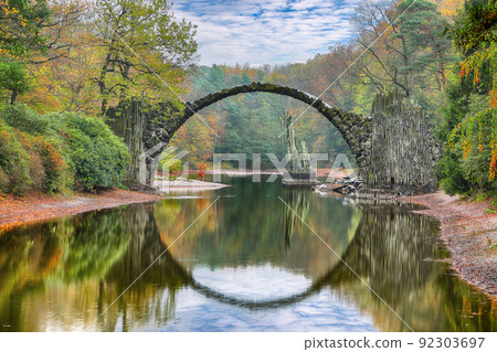 Fabulous autumn landscape in Azalea and Rhododendron Park Kromlau. Rakotz Bridge (Rakotzbrucke, Devil's Bridge) Fabulous autumn landscape in Azalea and Rhododendron Park Kromlau. Rakotz Bridge (Rakotzbrucke, Devil's Bridge) 92303697