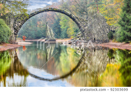 Fabulous autumn landscape in Azalea and Rhododendron Park Kromlau. Rakotz Bridge (Rakotzbrucke, Devil's Bridge) 92303699
