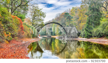 Astonishing autumn landscape in Azalea and Rhododendron Park Kromlau. Rakotz Bridge (Rakotzbrucke, Devil's Bridge) Astonishing autumn landscape in Azalea and Rhododendron Park Kromlau. Rakotz Bridge (Rakotzbrucke, Devil's Bridge) 92303700