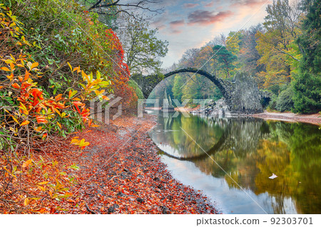 Astonishing autumn landscape in Azalea and Rhododendron Park Kromlau. Rakotz Bridge (Rakotzbrucke, Devil's Bridge) Astonishing autumn landscape in Azalea and Rhododendron Park Kromlau. Rakotz Bridge (Rakotzbrucke, Devil's Bridge) 92303701
