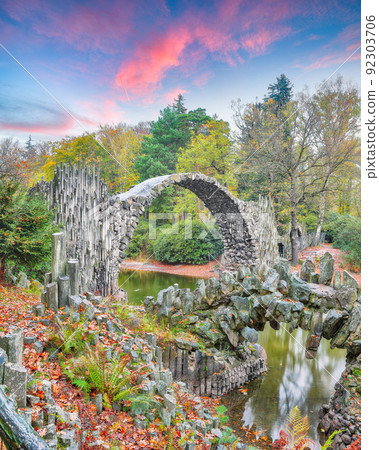 Fabulous autumn landscape in Azalea and Rhododendron Park Kromlau. Rakotz Bridge (Rakotzbrucke, Devil's Bridge) 92303706