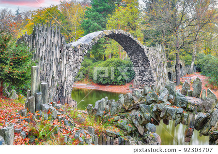 Unbelievable autumn landscape in Azalea and Rhododendron Park Kromlau. Rakotz Bridge (Rakotzbrucke, Devil's Bridge) Unbelievable autumn landscape in Azalea and Rhododendron Park Kromlau. Rakotz Bridge (Rakotzbrucke, Devil's Bridge) 92303707