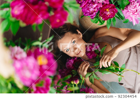 an attractive woman on the floor with a bouquet of peonies. an attractive woman on the floor with a bouquet of peonies. 92304454