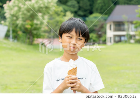 Asian kid eating soft serve ice cream in a fresh green park Asian kid eating soft serve ice cream in a fresh green park 92306512