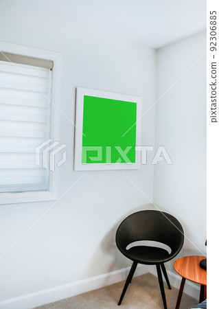 A reading chair armchair with a lamp, blanket and a open book. Empty white wall in simple living room interior. Copy space 92306885